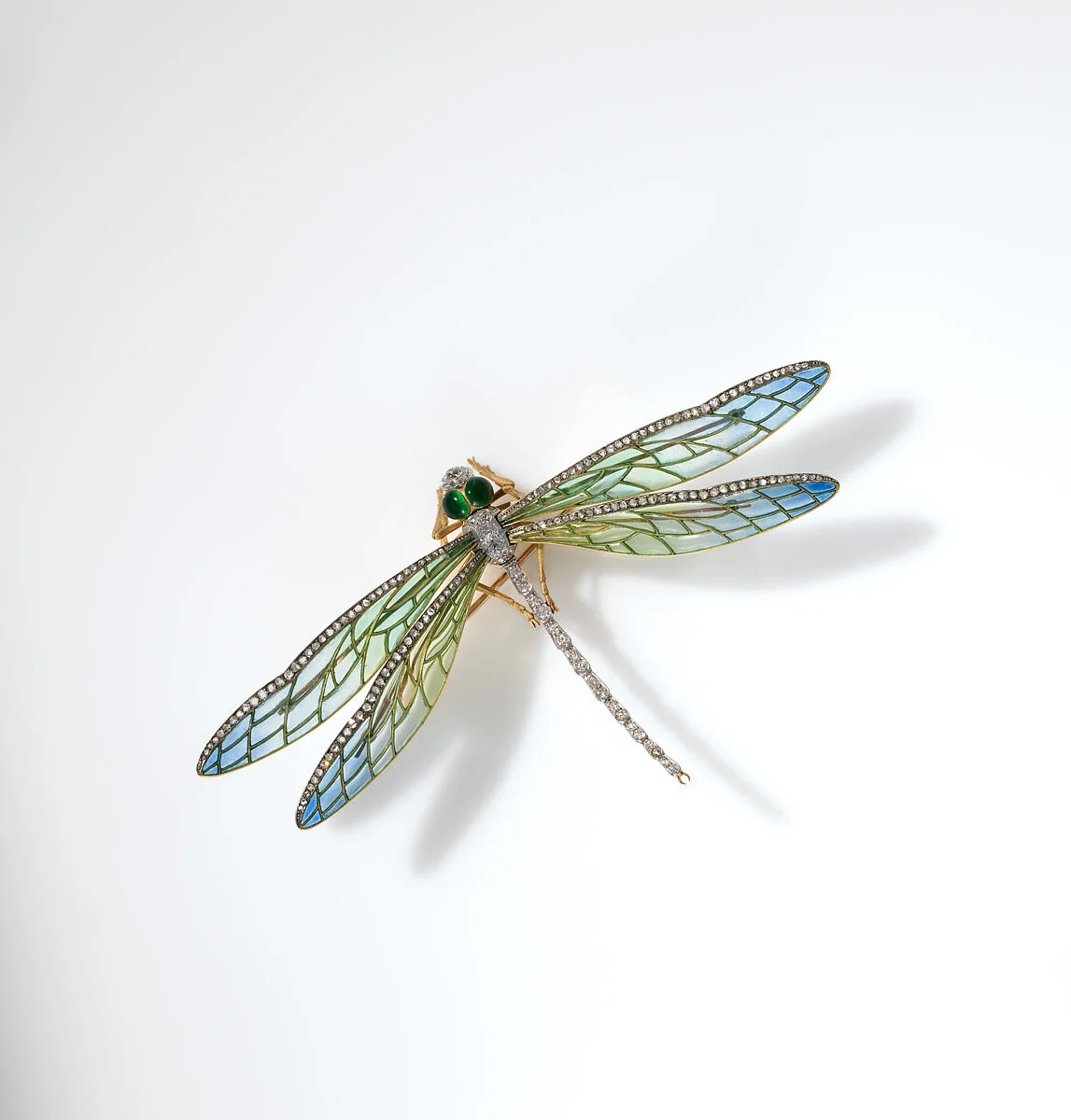 Fotografia museale della spilla Dragonfly: ali smaltate blu e verdi, corpo sottile e occhi verdi.