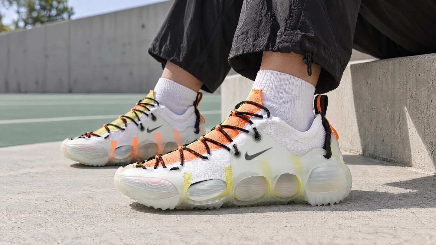 Visual AI: scarpe Nike ISPA Link Axis bianche e arancioni indossate accanto a un campo.